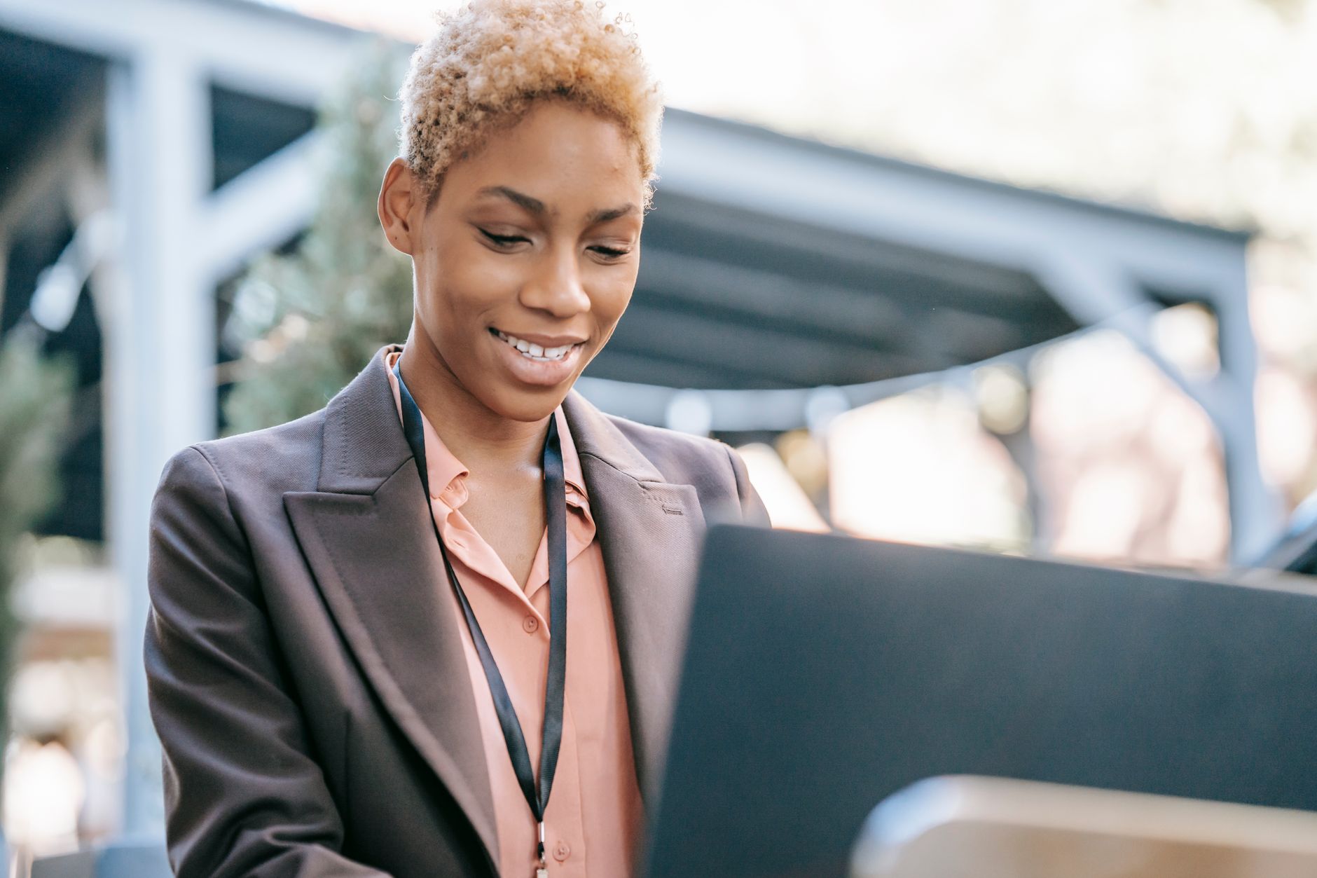 A confident businesswoman working outdoors on a laptop, illustrating the flexibility of remote support work.